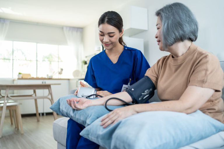 Caregiver and doctor examining older patient, blood pressure monitoring for personal wellness.