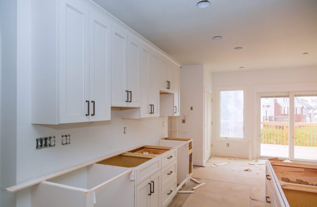 Newly installed white kitchen cabinets and countertops during a home renovation project.