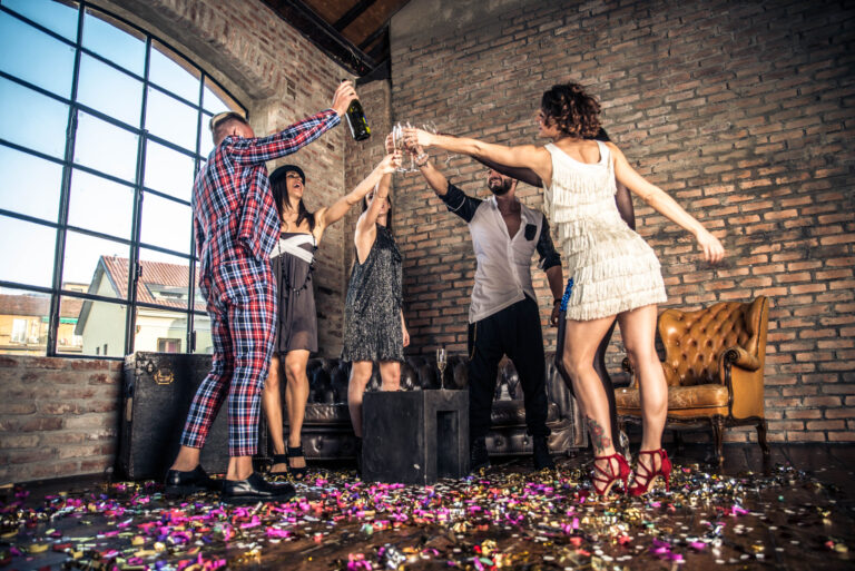 Friends celebrating with champagne and confetti at a small party.