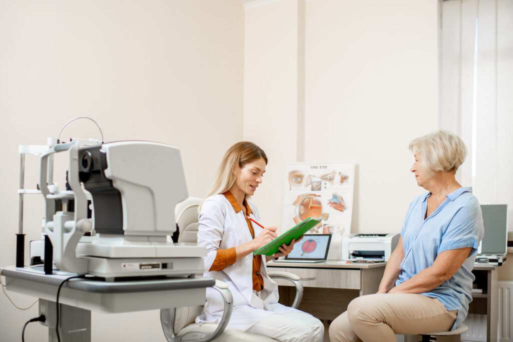 Senior patient with ophthalmologist in office, eye examination equipment and chart.