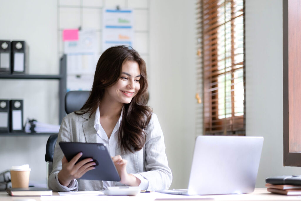 Asian businesswoman using calculator and laptop for financial reconciliation automation.