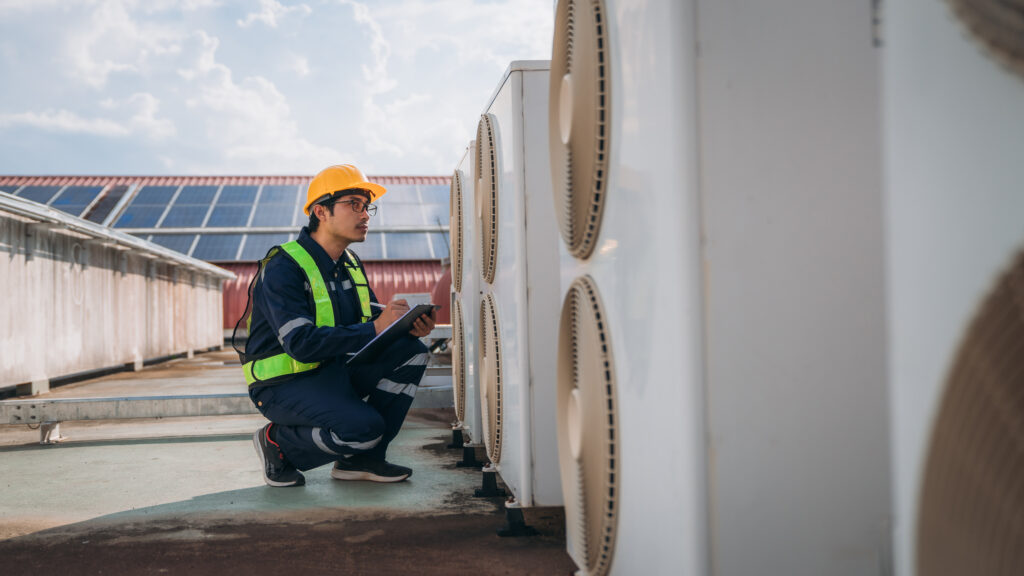 HVAC engineer inspecting air conditioning unit with clipboard, maintaining heating and cooling system.