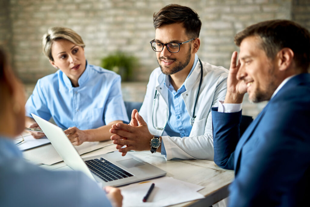 Healthcare administrators and doctors collaborating on computer for streamlined operations.