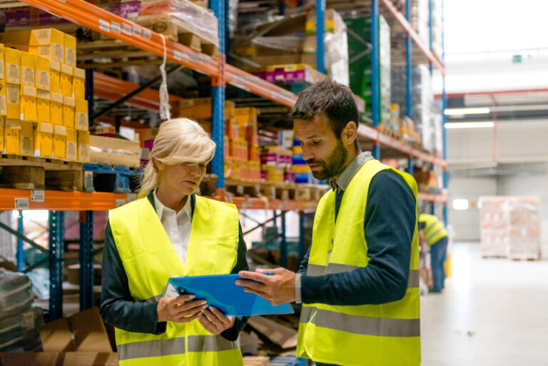Warehouse workers reviewing inventory records and equipment management.