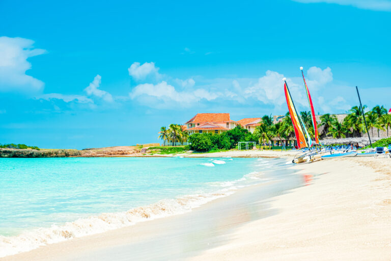 Idyllic tropical beach vacation destination and colorful sailboats on turquoise water