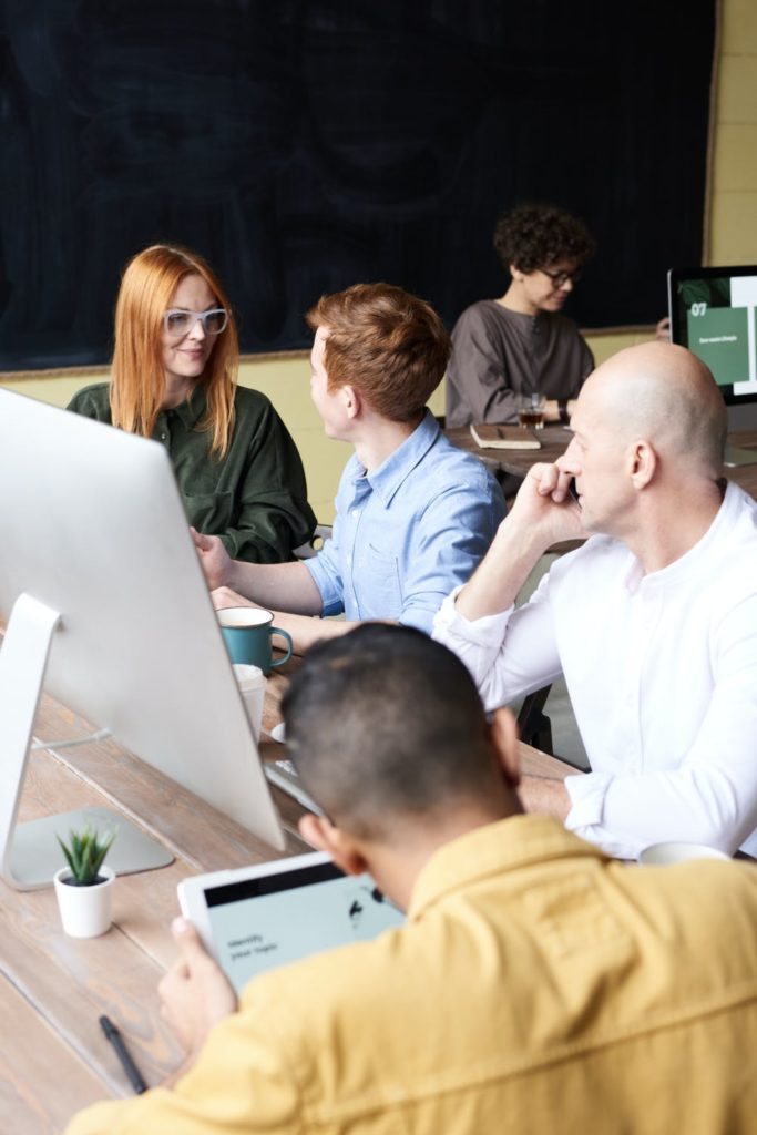 a group of people sitting around a table looking at a laptop