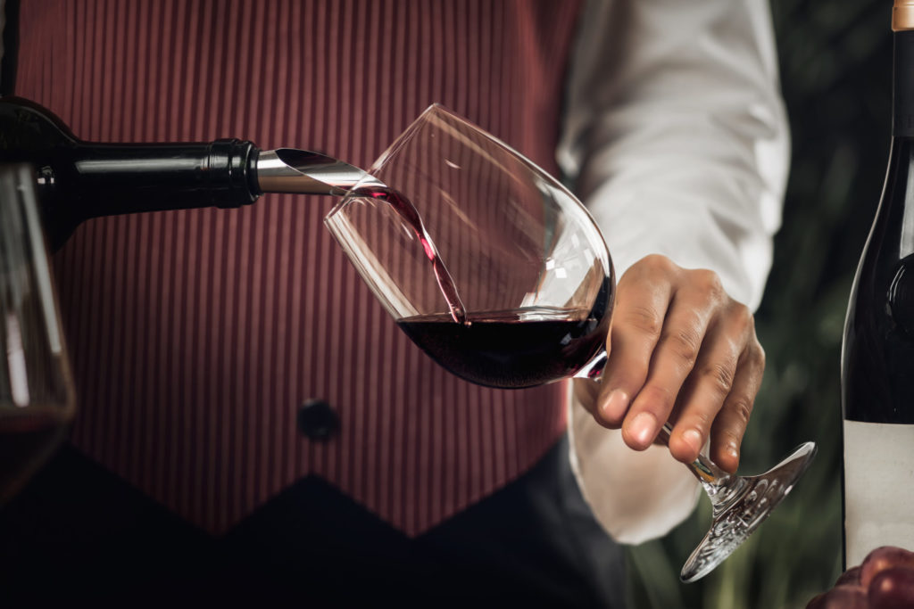 a person pouring wine into a glass